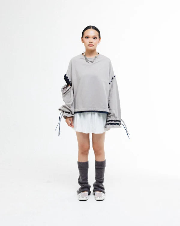 Person wearing a gray oversized sweater by Wad Studio with black accents on a white background