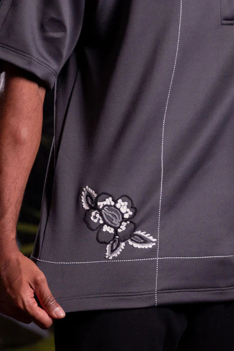 Close-up of a dark gray shirt with a floral embroidery detail by Nona on a blurred background