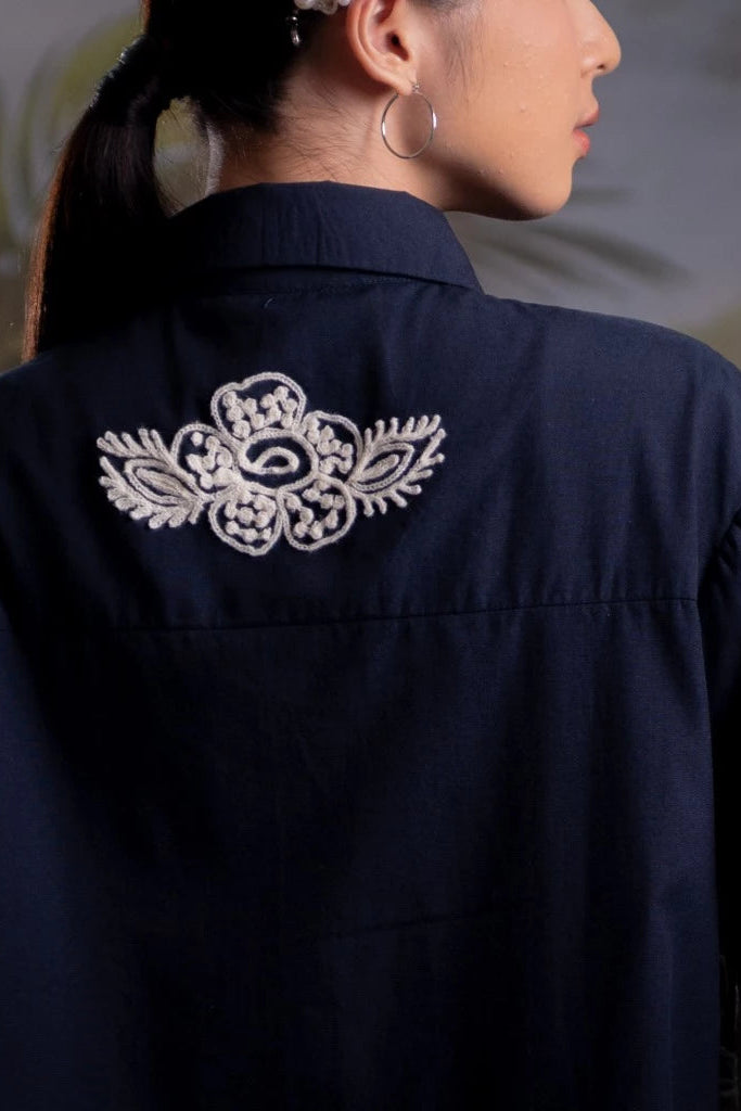 Navy blue shirt with white floral embroidery on the back by Nona, worn by a person.