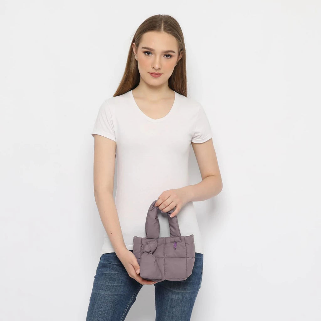 Woman holding a purple handbag by Hunting Fields against a white background
