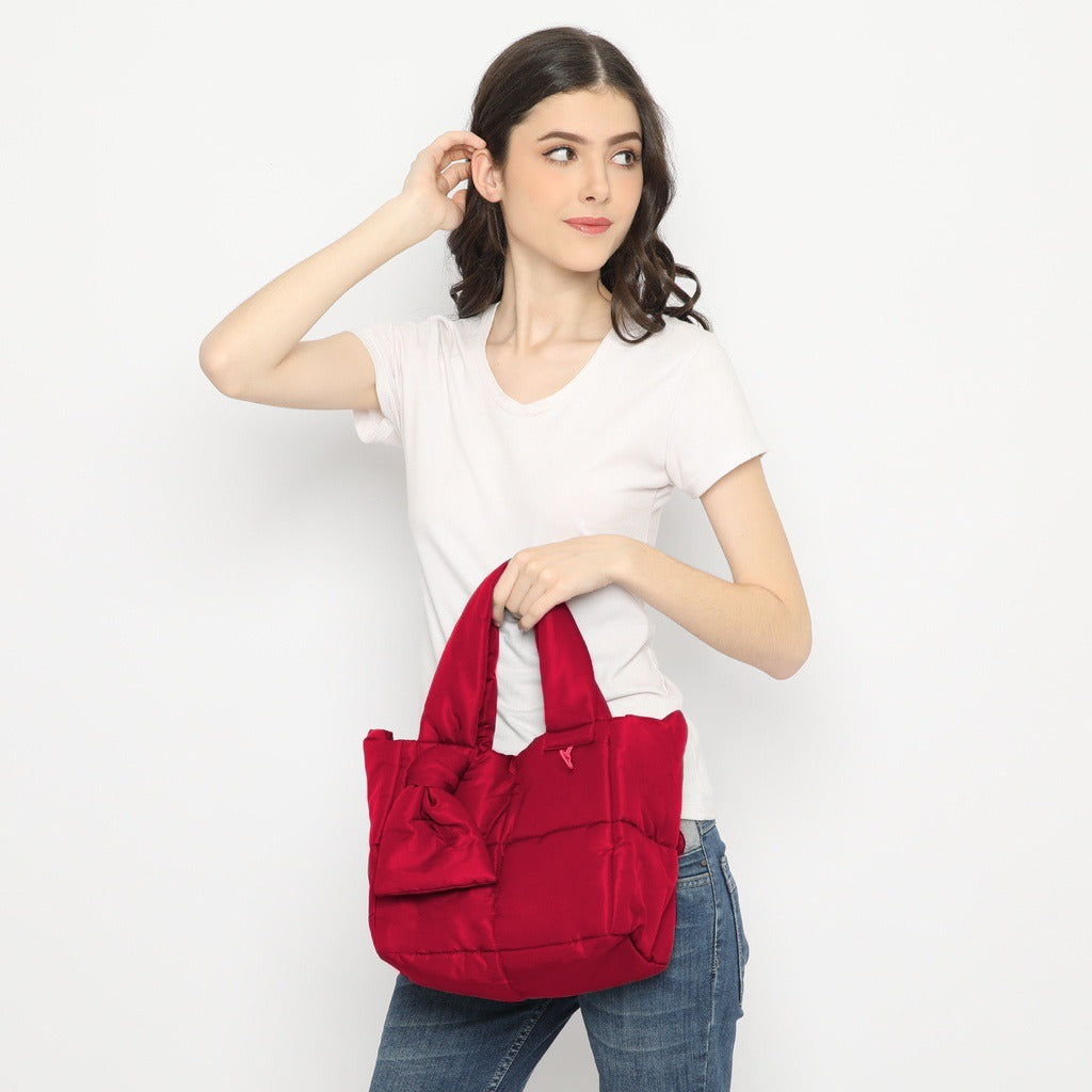 A person holding a red nylon handbag by Hunting Fields.