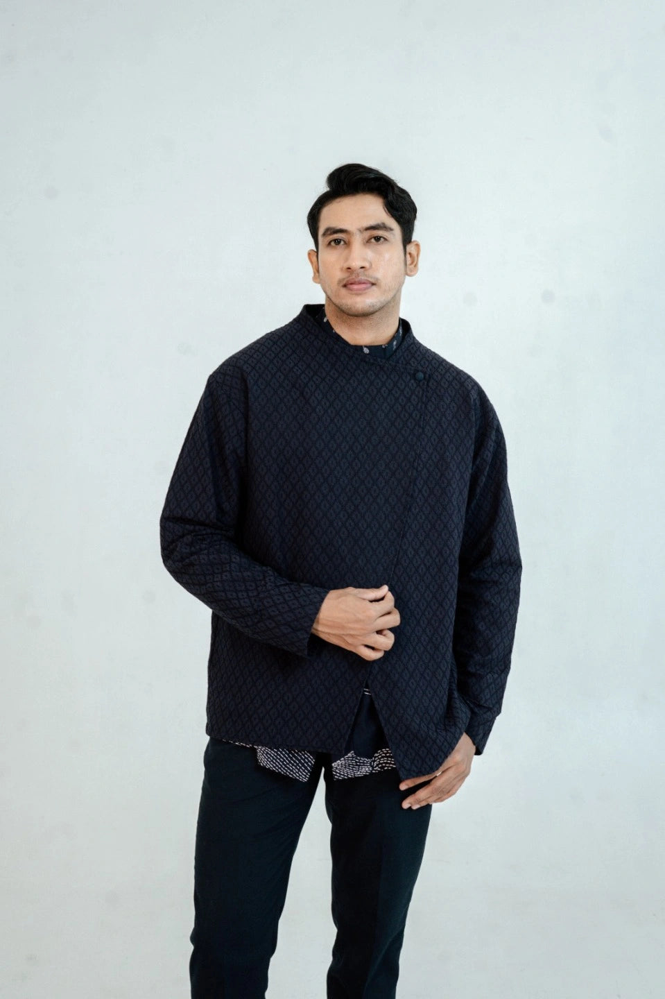 Man wearing a navy textured beskap by Damakara against a plain background