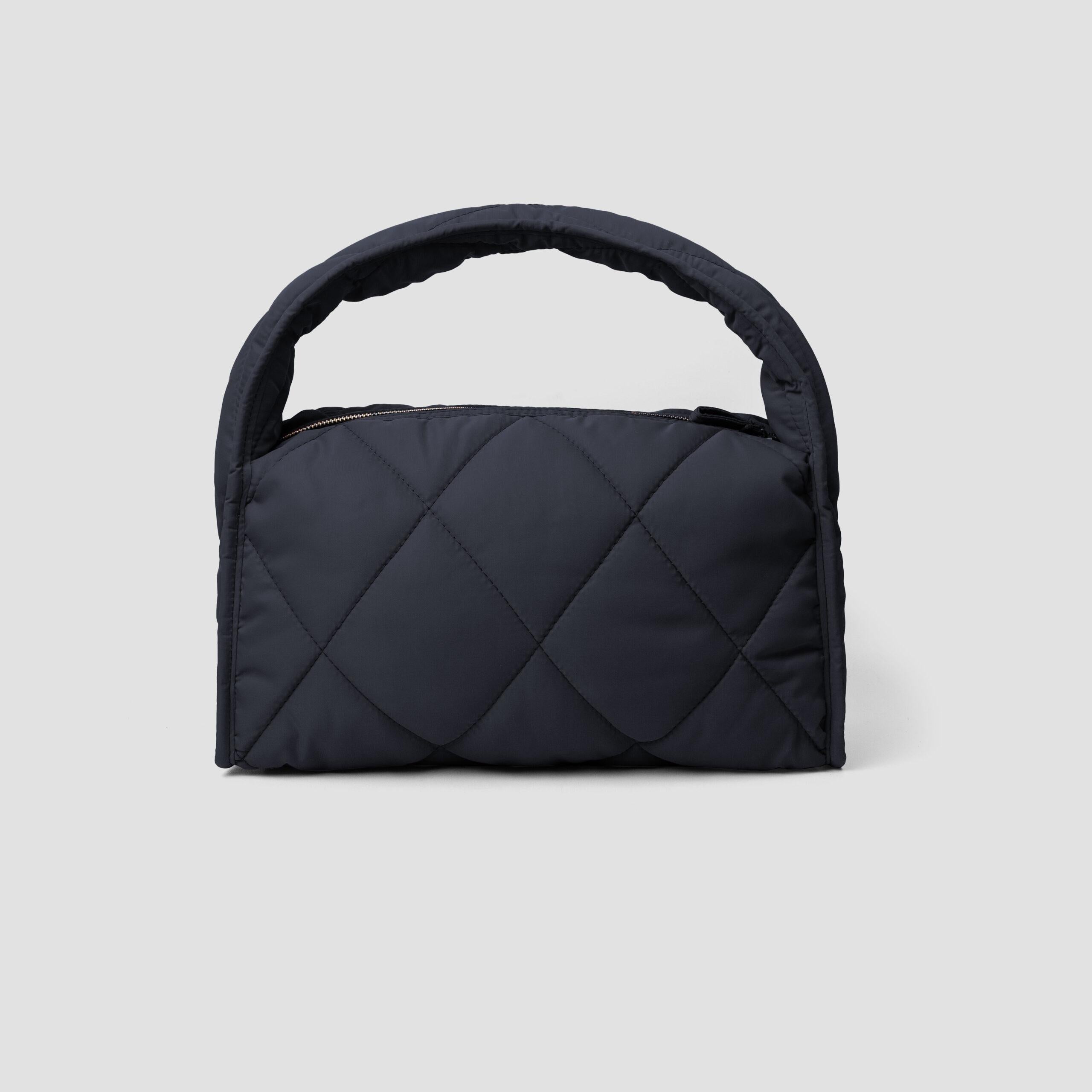 Black quilted women's handbag by MKS Shoes on a light gray background.
Tas tangan wanita berlapis dari MKS Shoes berwarna hitam dengan latar belakang abu-abu muda.