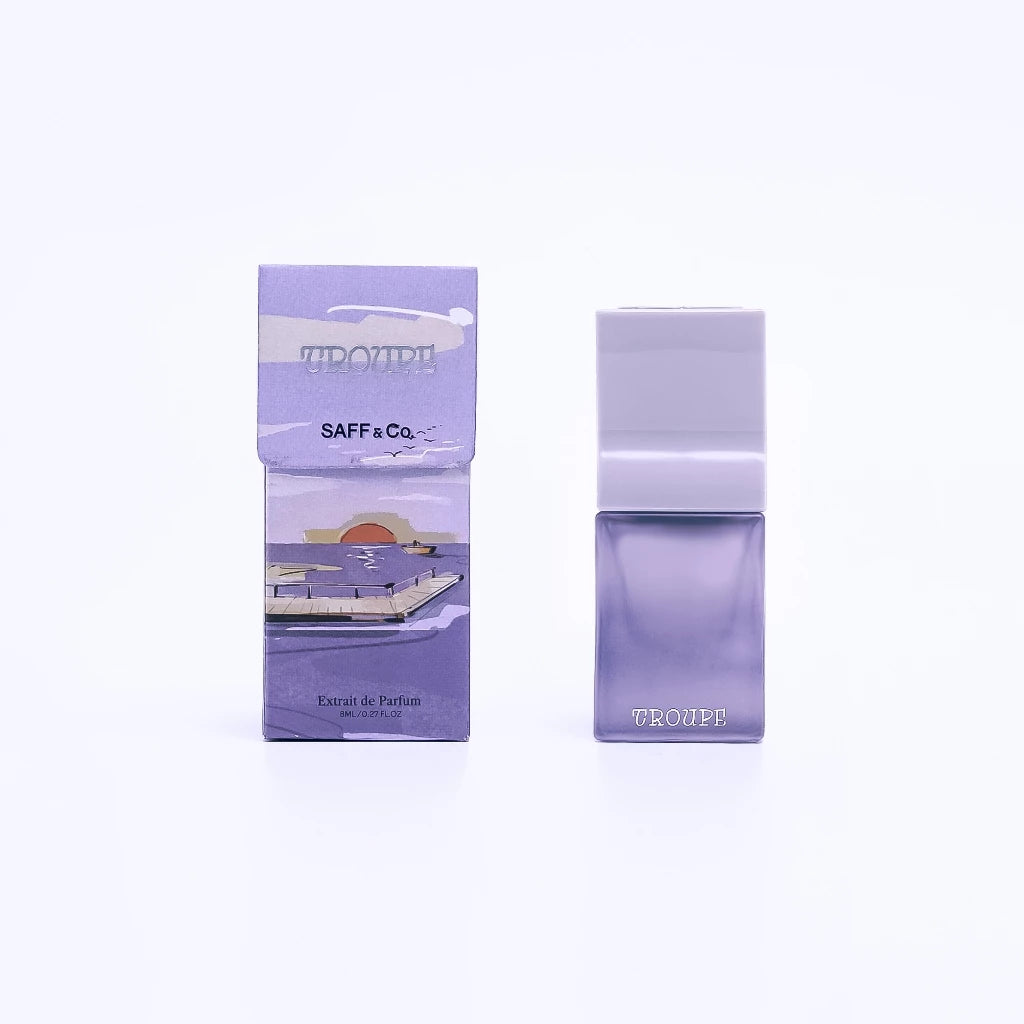 A travel-sized bottle of Saff & Co. Extrait De Parfume named 'TROUPE' next to its packaging, both featuring a purple color scheme.