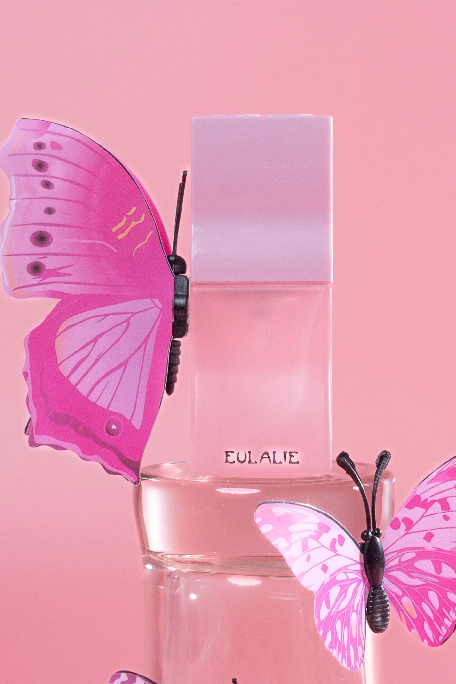 Pink perfume bottle by Saff & Co with pink butterfly design on a pink background