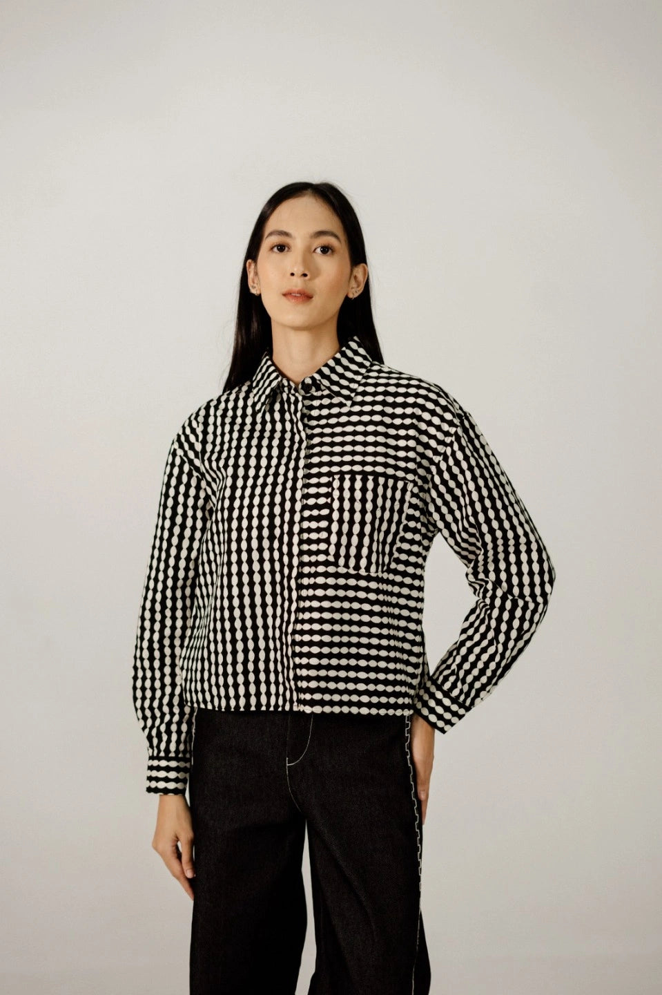 Person wearing a black and white checkered longsleeves shirt by Damakara against a plain background