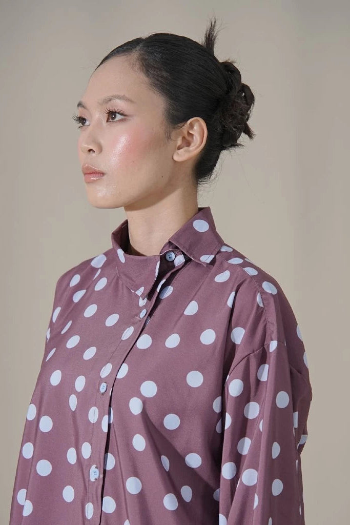 Woman wearing a brown polka dot shirt by Tuff Puff against a plain background