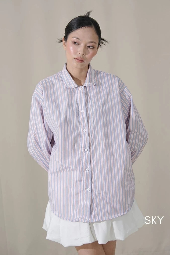 Woman wearing a striped shirt by Tuff Puff paired with a white mini skirt against a plain background