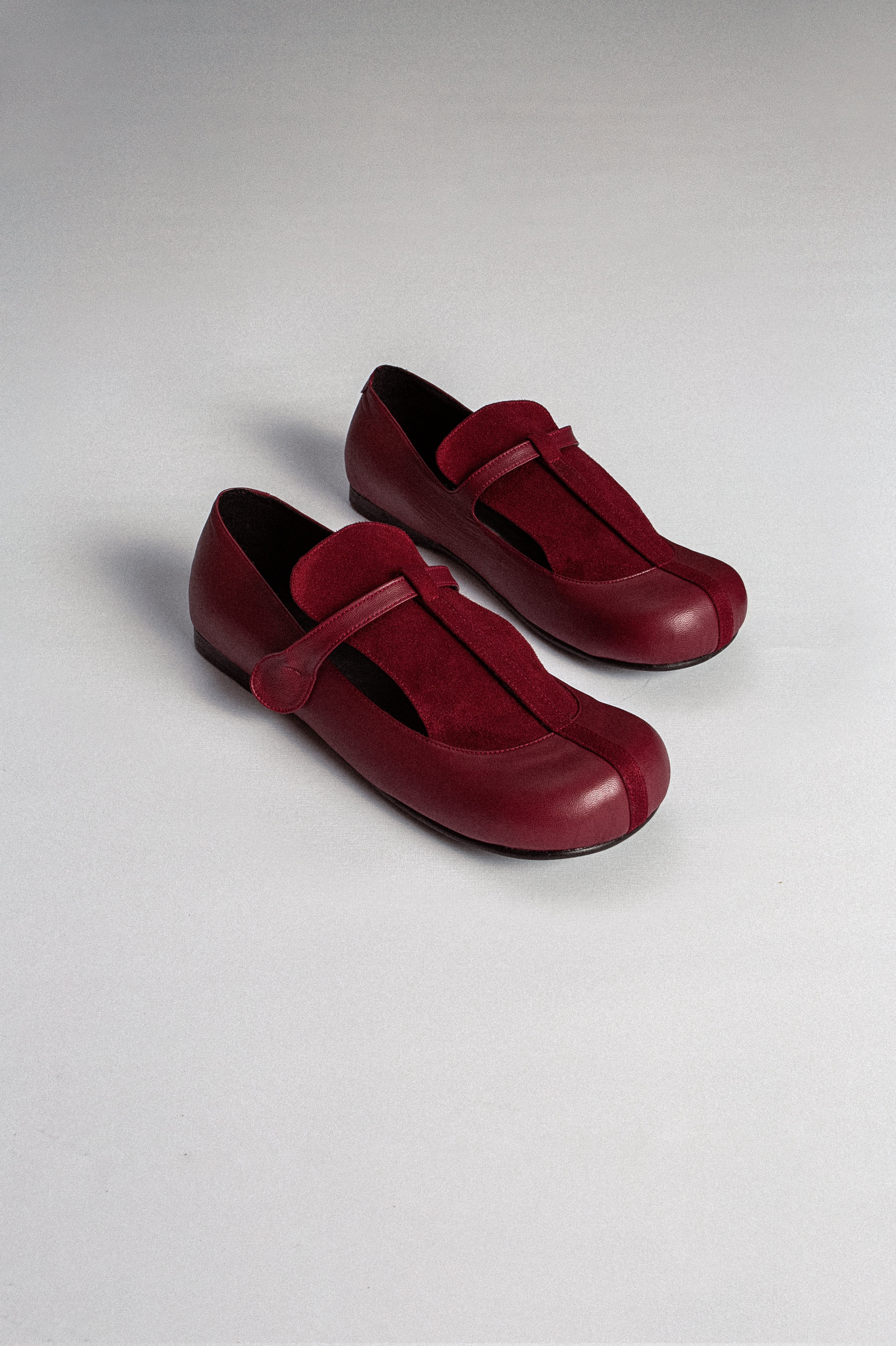 A pair of red women's leather flat shoes with a T-bar design and Mary Jane flats style from MTW on a plain background.