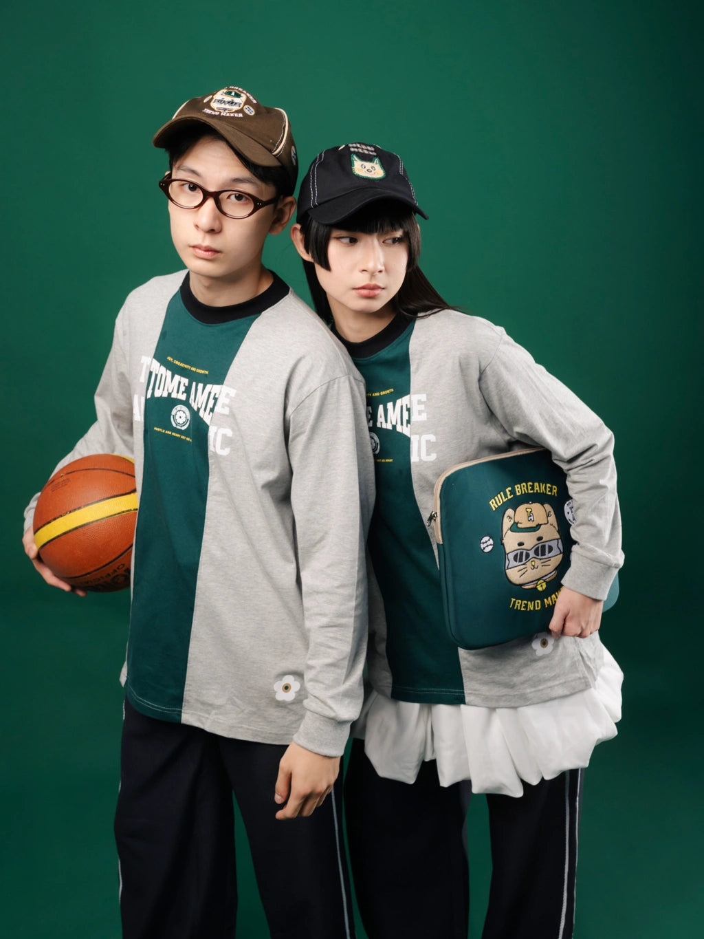 Two people wearing matching Tome Ame longsleeve with a basketball and bag against a green background