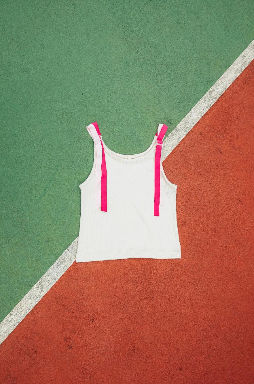 White tank top by Wad Studio with pink straps on a green and red floor
