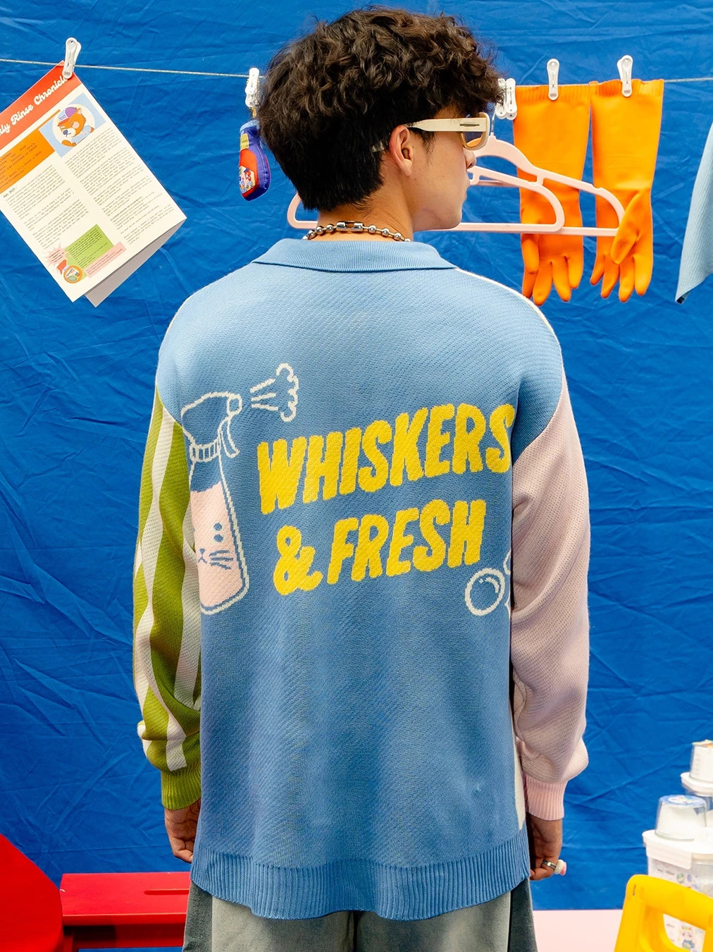 Person wearing a colorfull knitted cardigan by Oh.Irv with 'Whiskers & Fresh' text and graphics at the back.