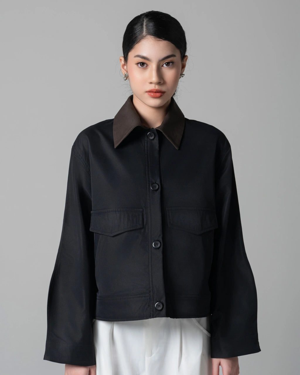 Person wearing a black trucker jacket with a brown collar by Kajuaruna against a gray background