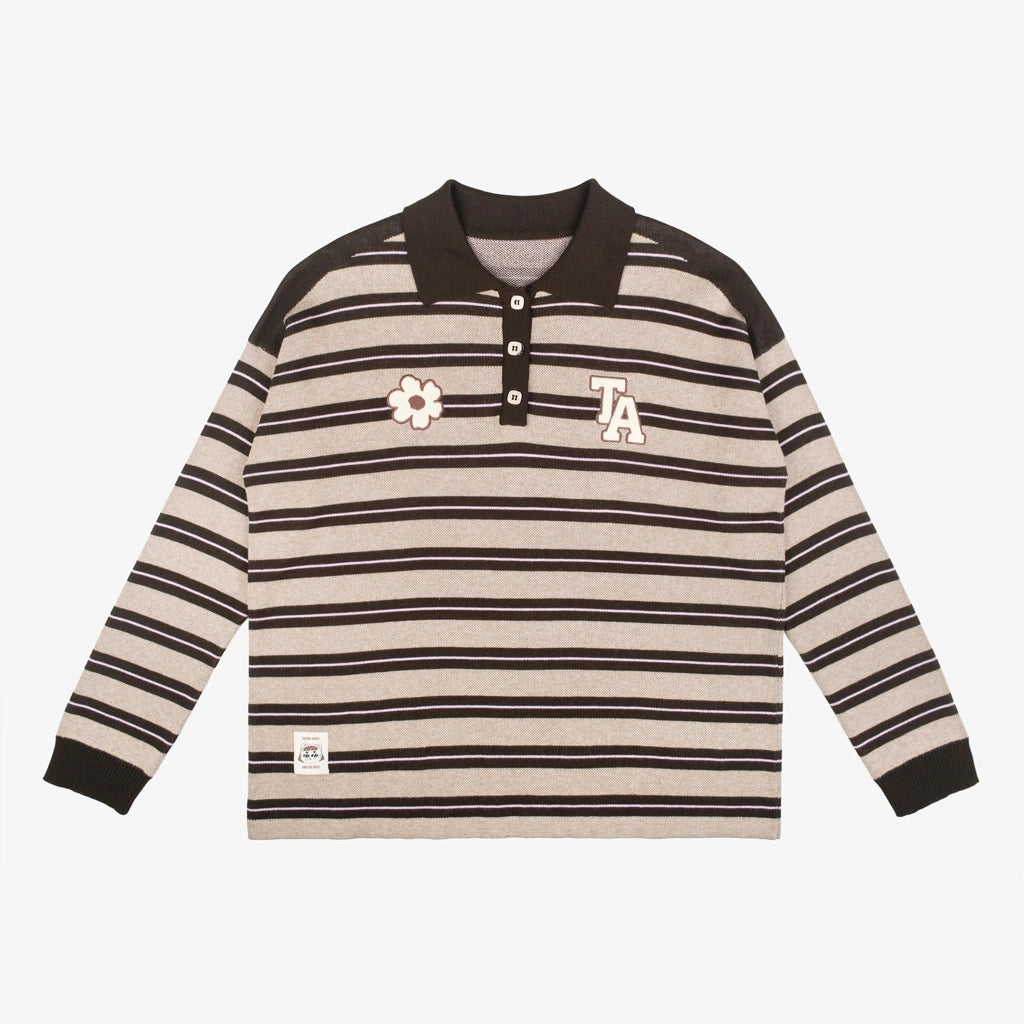 A long-sleeve knit polo shirt by Tome Ame with horizontal beige and dark brown stripes, featuring a dark brown collar and cuffs, a small white flower patch on the left chest, and a white embroidered 'LA' on the right chest.