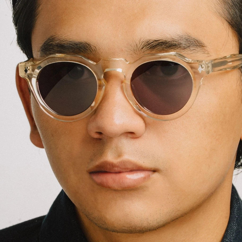 Close-up of a person wearing round sunglasses by Cool Uncle with a clear frame.