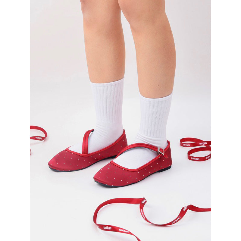 A pair of red women’s Mary Jane flats shoes by Takkan with small white dot patterns, worn with white ribbed socks. The shoes feature adjustable straps and are styled with red ribbons on the floor for a playful touch.

Sepatu flat wanita model Mary Jane berwarna merah dengan pola titik putih kecil dari Takkan, dipadukan dengan kaus kaki putih bergaris. Dilengkapi tali yang dapat disesuaikan dan dihiasi pita merah di lantai untuk tampilan yang manis dan playful.