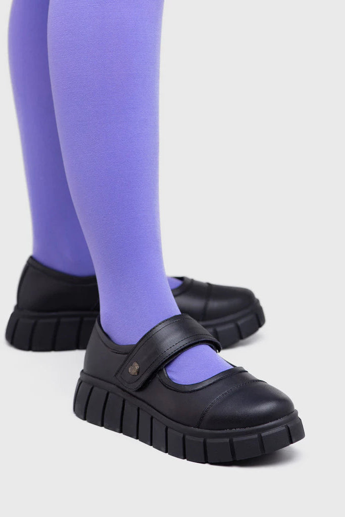 Black mary jane shoes by Adorable Projects with a strap worn with purple tights on a light gray background