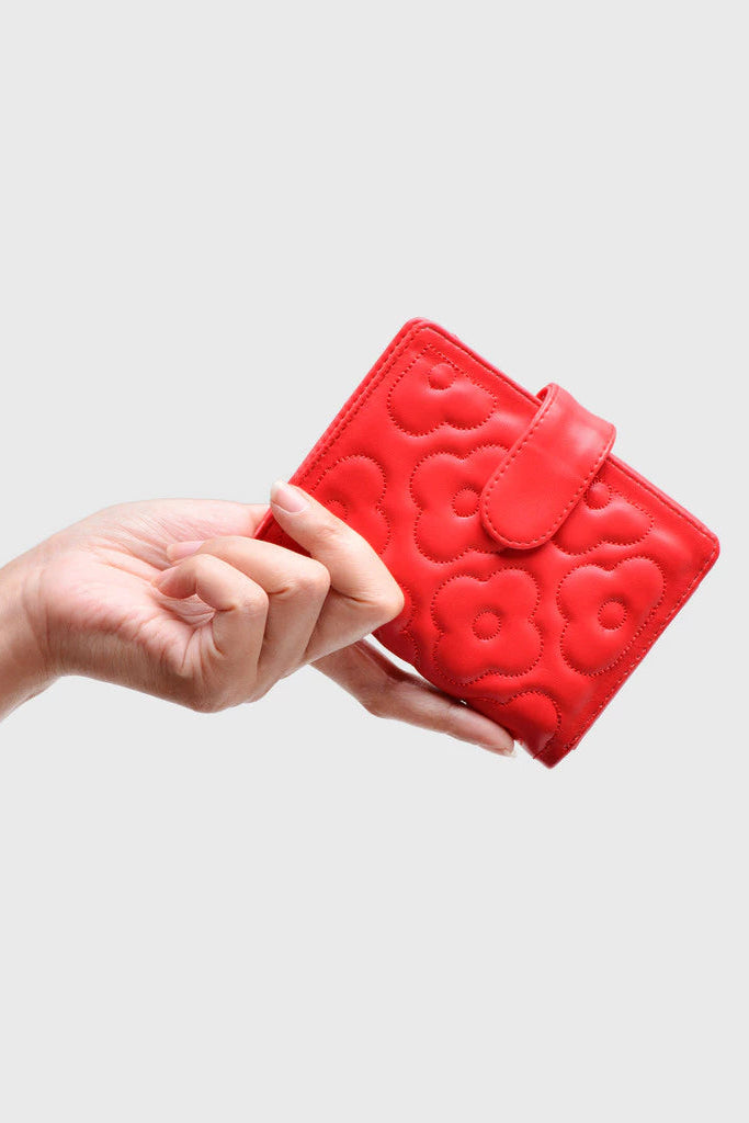 Red wallet by Adorable Projects with floral patterns held by a hand against a light gray background