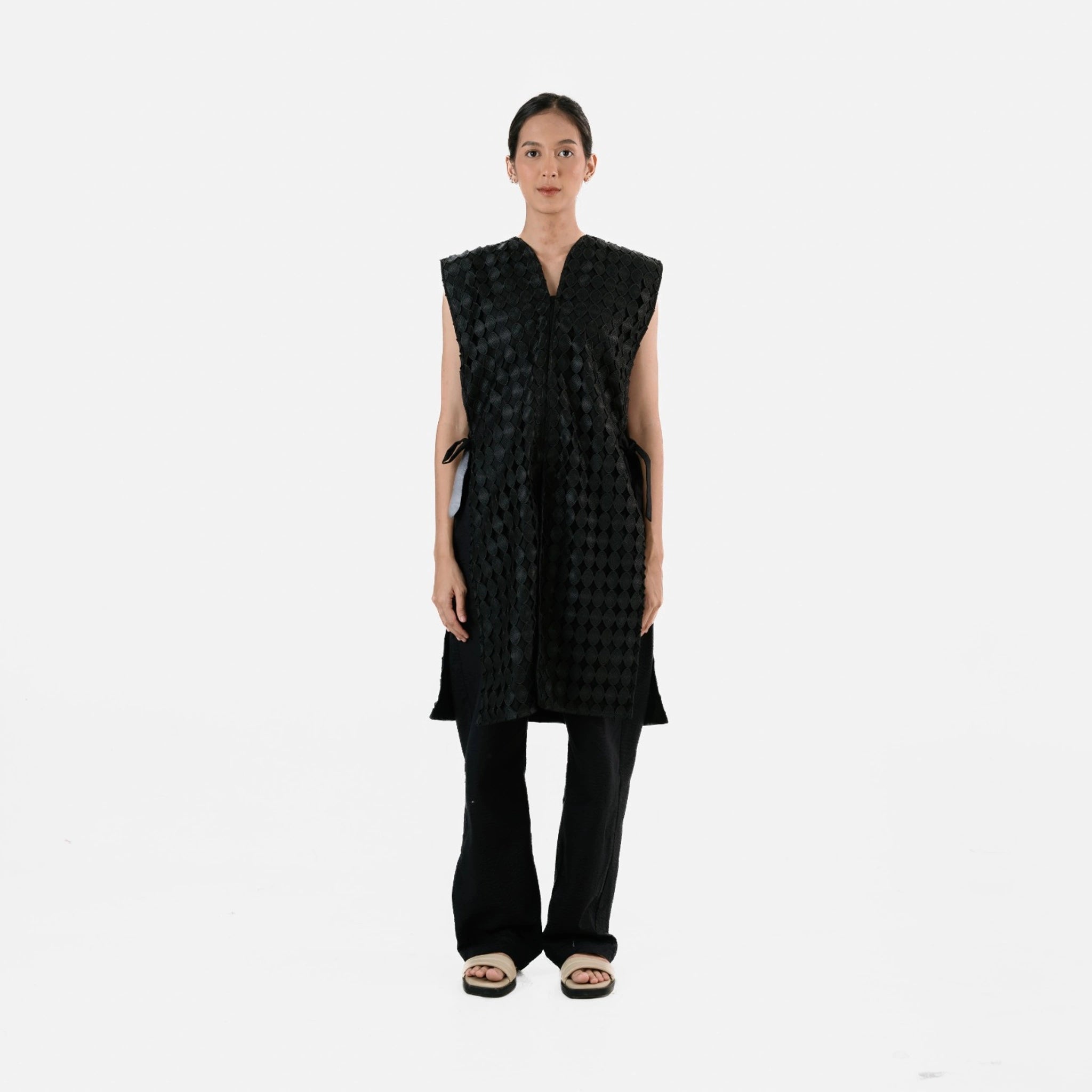 Woman wearing a black sleeveless checkered long vest by Damakara on a white background