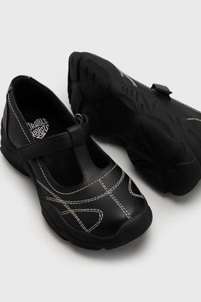 Black leather mary jane shoes by Adorable Projects with a strap on a white background