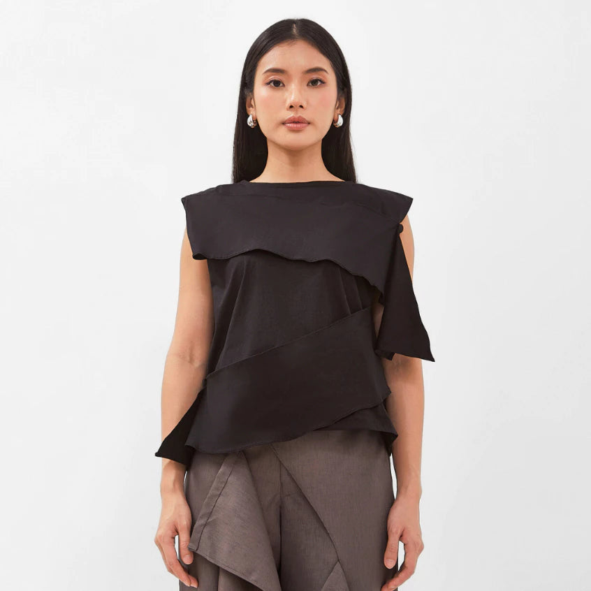 Woman wearing a black layered top by Isoos Studios and gray skirt on a white background