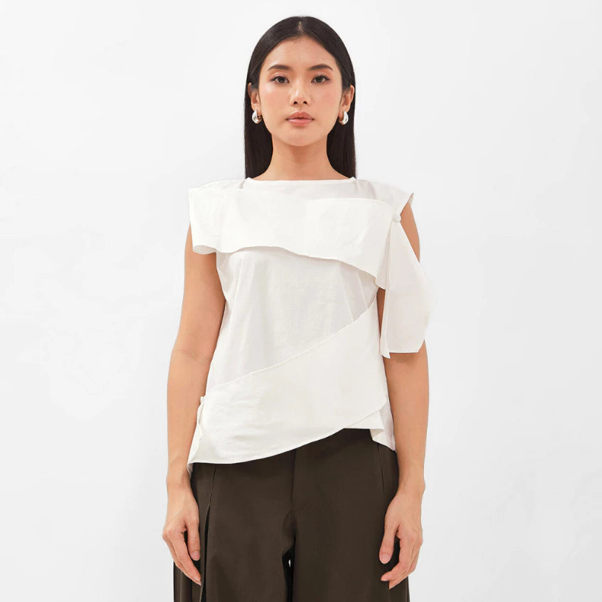 Woman wearing a white sleeveles top by Isoos Studios with a plain background