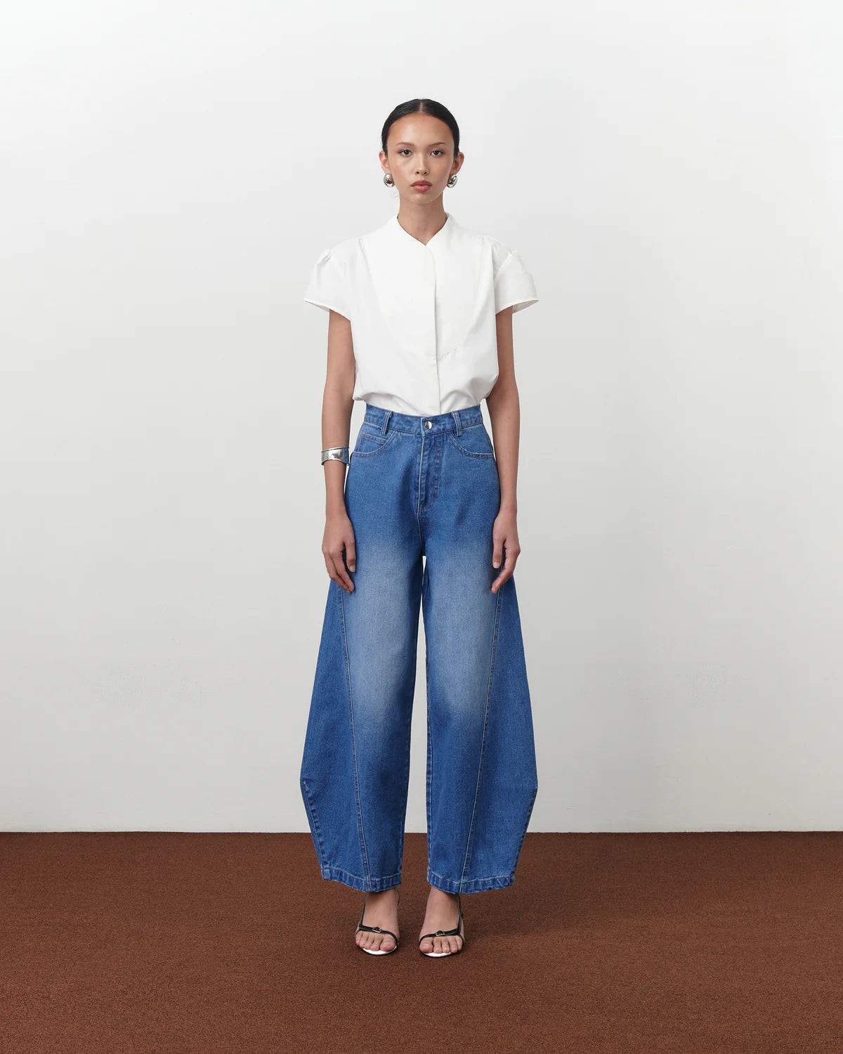 Person wearing a white shirt and blue jeans by Achete de Nous on a plain background