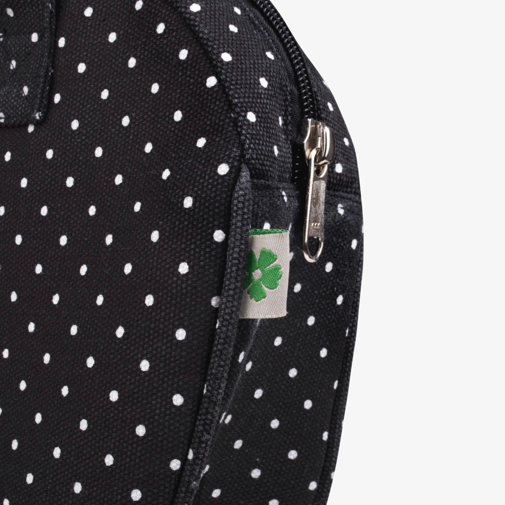 Black polka dot bag with a visible brand tag featuring a green clover symbol on a white background.