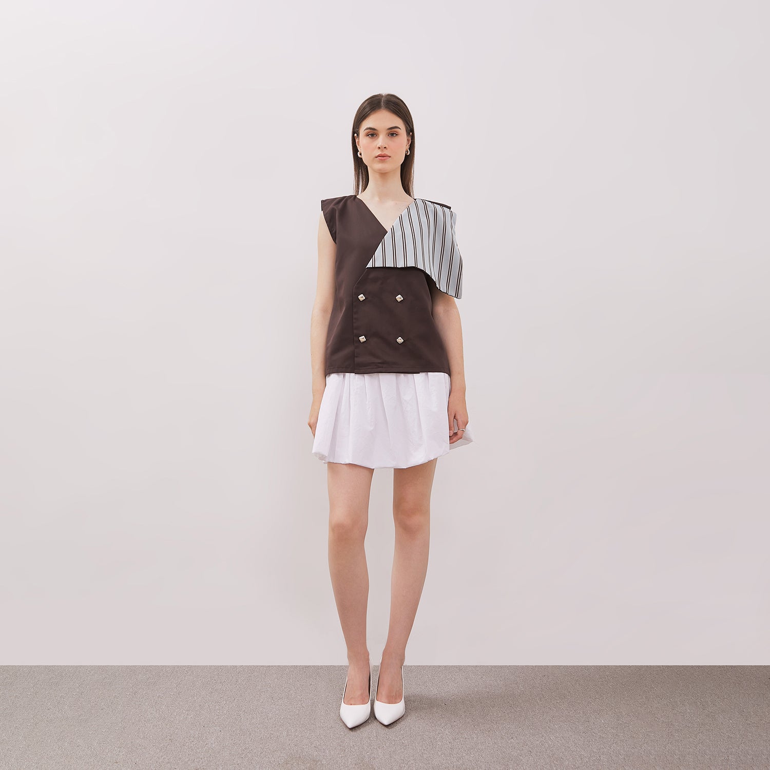 Woman wearing Athena Vest, a sleeveless top with a geometric pattern, and white skirt against a plain background