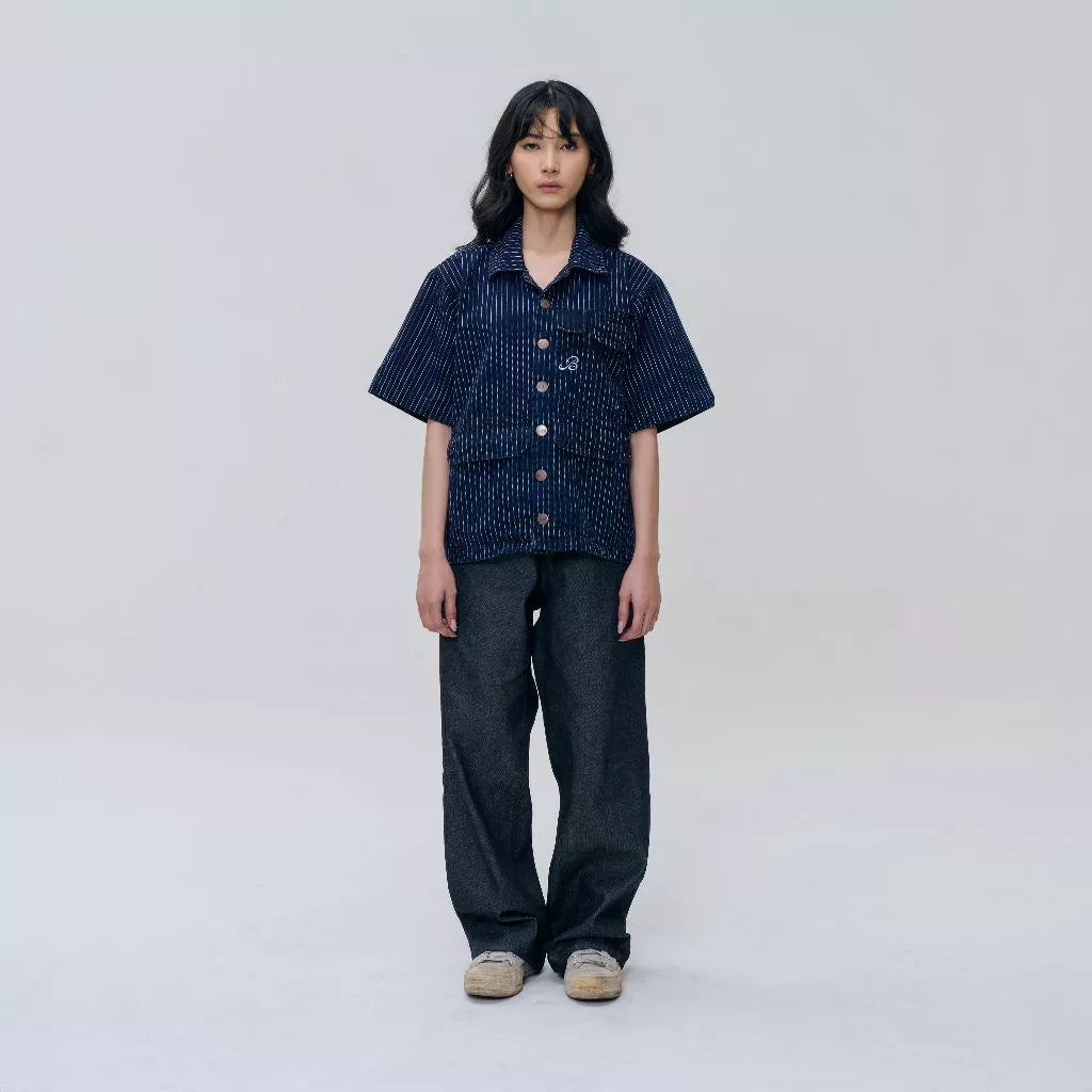 Person wearing a dark blue stripped shirt and black pants on a white background