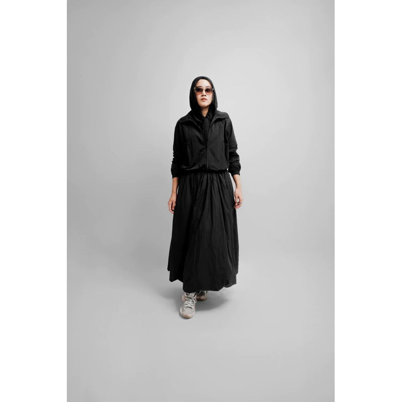Woman wearing a flowy black maxi balloon skirt styled with a black top and outerwear.