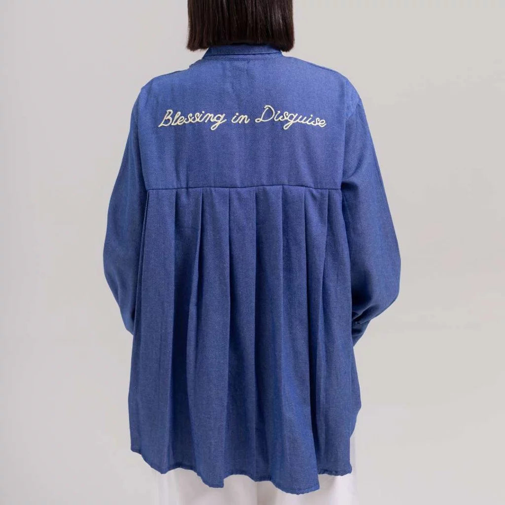 Blue shirt by Tuff Puff with 'Blessing in Disguise' text on the back against a plain background