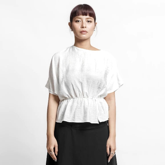 Person wearing a white blouse by Isoos Studios with a plain background