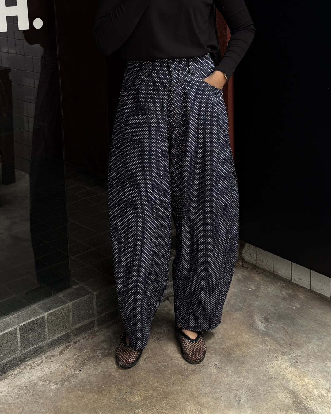 Person wearing patterned barrel pants standing against a dark wall.

Seseorang mengenakan celana barrel bermotif sedang berdiri di depan dinding gelap.