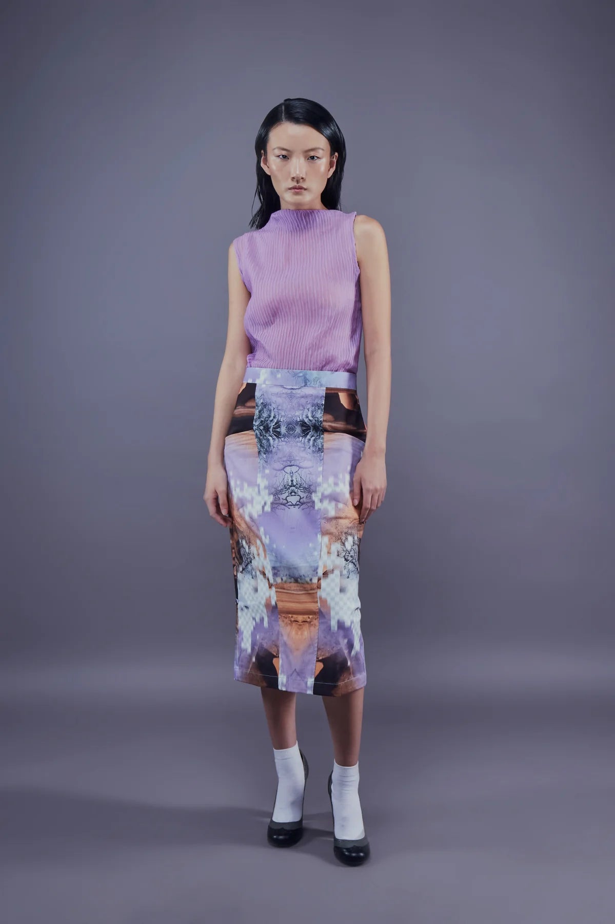 A model wearing a calf-length skirt with a colorful canyon print. The skirt has a printed pattern with pockets on the front.