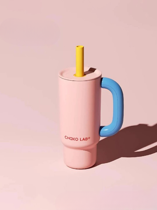 A pink Chako Lab Baba Cup with a blue handle and a yellow straw, placed against a pink background.