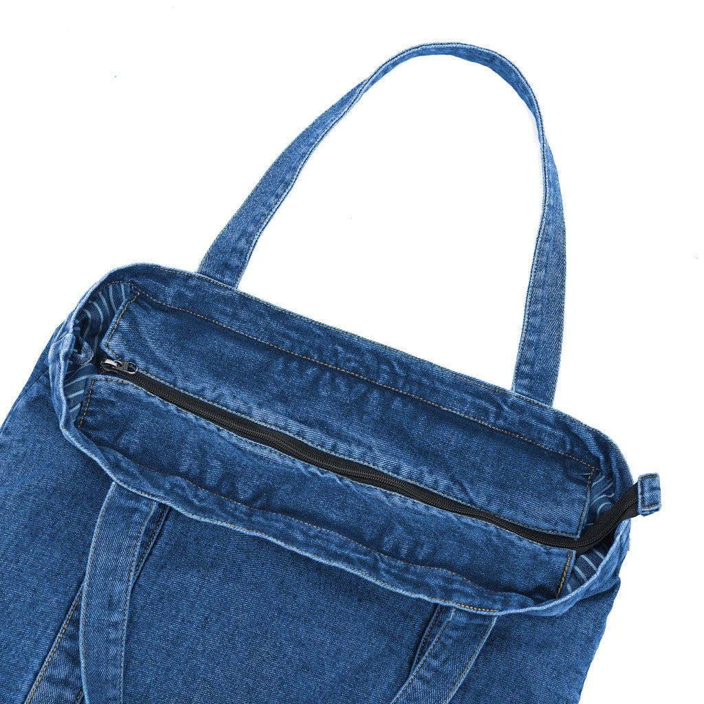 Blue denim women's totebag with a zipper on a white background.

Tas tote wanita berwarna biru denim dengan resleting pada latar belakang putih.