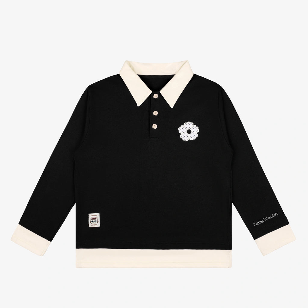 A long-sleeve black polo shirt by Tome Ame with cream-colored collar, cuffs, and hem, featuring a white embroidered flower on the left chest and a small brand patch on the right sleeve.
