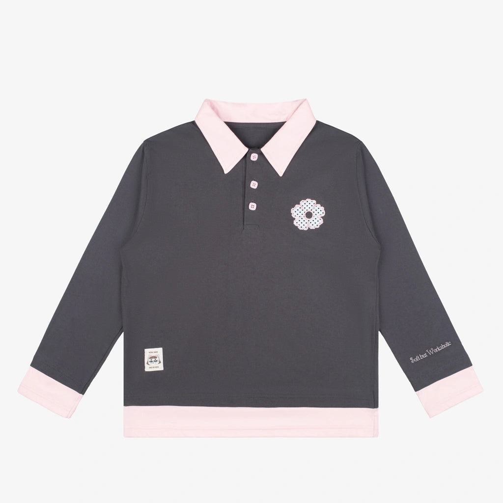A long-sleeve polo shirt by Tome Ame in dark gray with light pink accents on the collar, cuffs, and hem, featuring a small embroidered floral logo on the left chest.