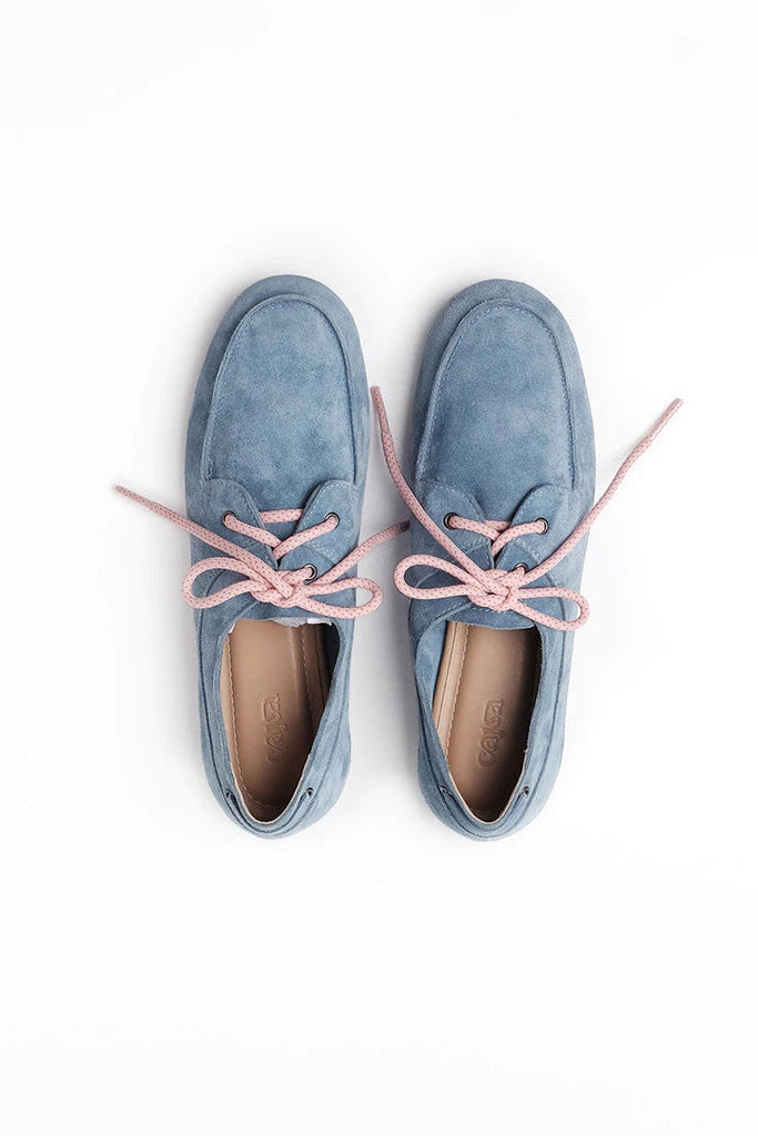 A pair of light blue suede boat-style flatshoes by Cajsa with contrasting light pink laces, shown from a top-down view on a white background.