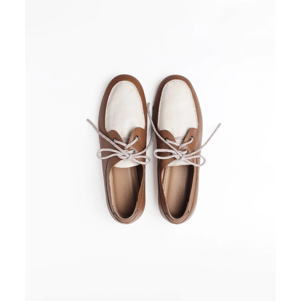 A pair of women's boat flatshoes by Cajsa in brown and off-white leather with light gray laces, shown from a top-down view on a white background.