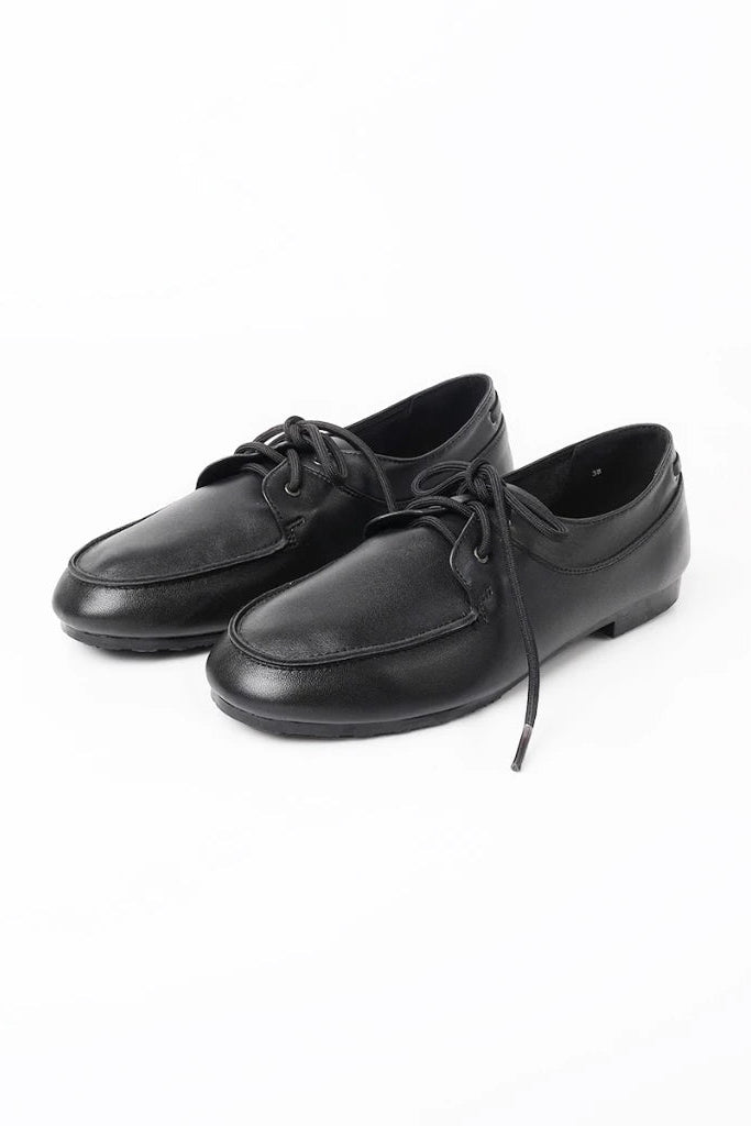 A pair of black leather lace-up flatshoes by Cajsa with a rounded toe and low flat heels, photographed on a clean white background.