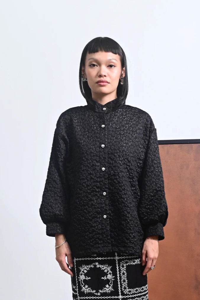 Person wearing a black patterned shirt by Tuff Puff with a plain background