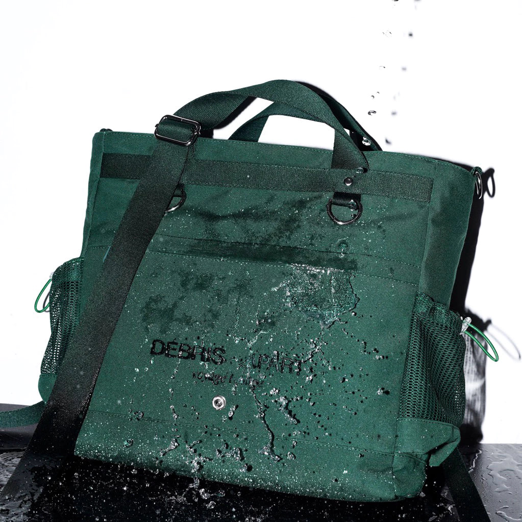 Dark green women’s tote bag made of canvas with a top handle and adjustable shoulder strap, featuring mesh side pockets. The surface is splashed with water, highlighting its water-resistant material and functional yet stylish design.

Tas wanita warna hijau tua berbahan kanvas dengan tali selempang dan handle atas, dilengkapi kantong samping berbahan mesh. Permukaan tas terlihat terkena percikan air, menampilkan fitur tahan air dan desain fungsional yang stylish.
