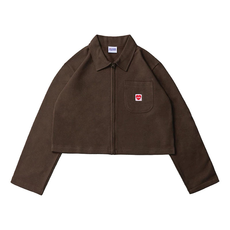 A brown crop jacket with a collar, long sleeves, and a front pocket, featuring a small red logo on the chest by notyourcompany.
