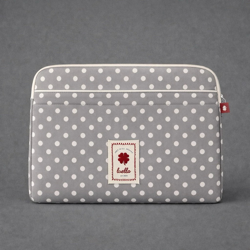 Light grey polka dot laptop sleeve by Luella with a brand label on a gray background