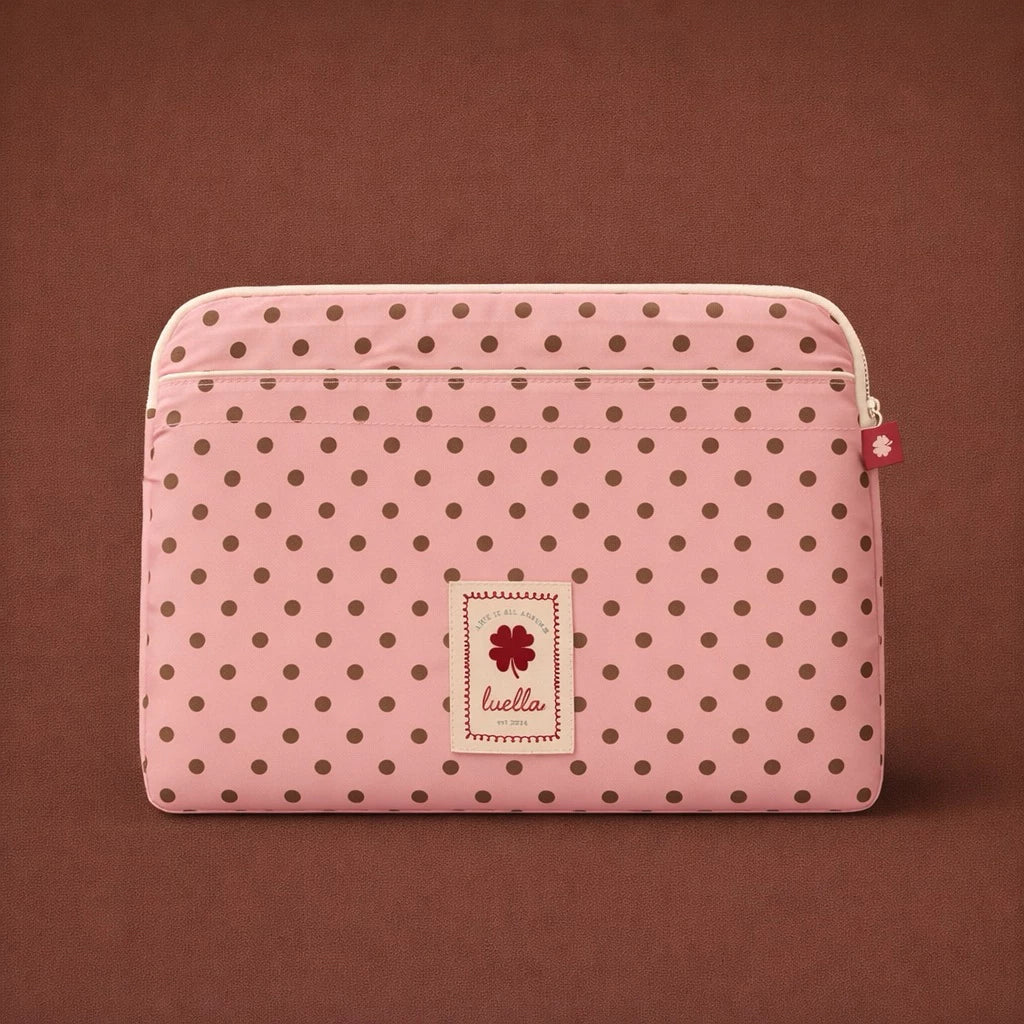 Pink polka dot laptop sleeve by Luella with a brand label on a brown background