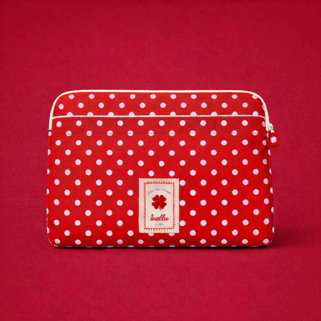 Red polka dot laptop sleeve by Luella with a brand label on a red background