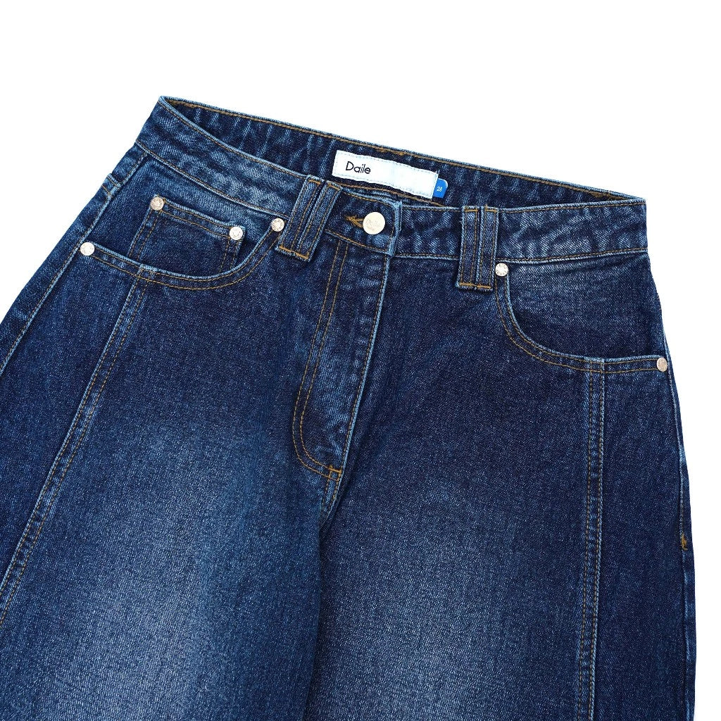 Close-up of blue barrel denim pants from Daile with a visible brand label on a white background