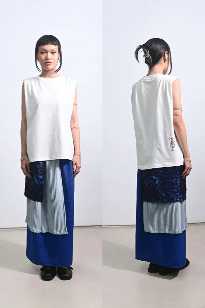 Woman wearing a white sleeveless top by Tuff Puff and blue pleated skirt, facing front and back.